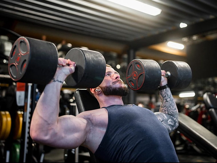 Un membre en développé haltères sur banc chez DBM Gym